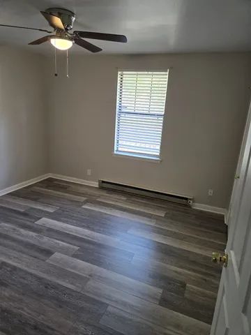 an empty room with wooden floor closet and windows