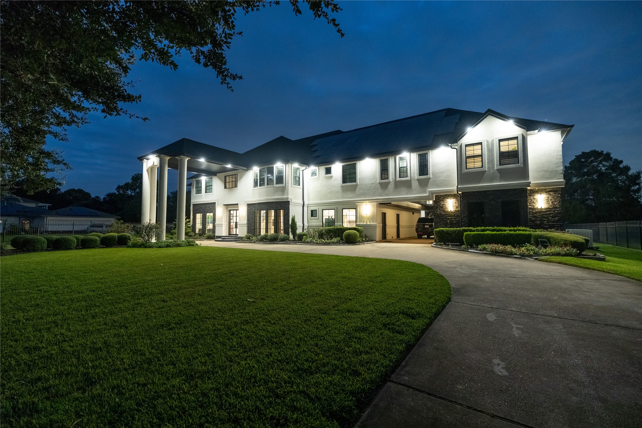 4002 Silver Ridge Boulevard Missouri City, TX 77459 - Photo 2 of 50 This is a spacious two-story home featuring a modern design with large windows, elegant columned entryway, well-manicured lawn, and ample outdoor lighting, captured at dusk to highlight its ambiance.