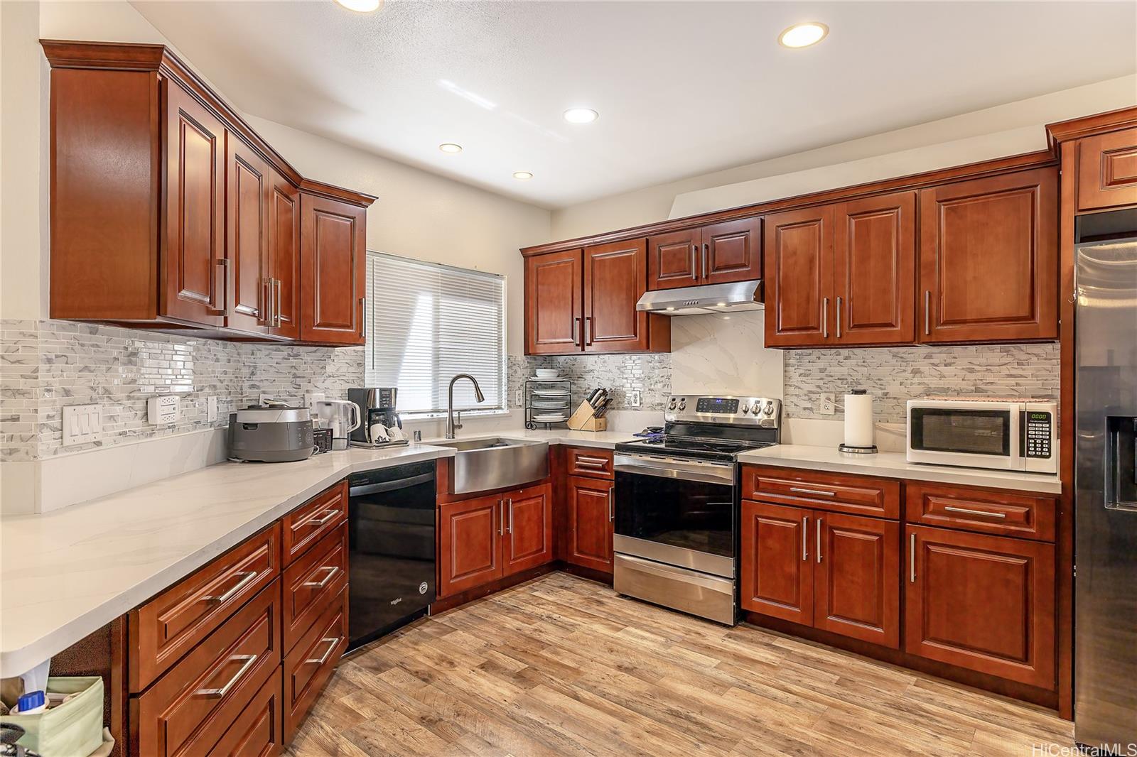 91-957 Laaulu Street, Unit 40F Ewa Beach, HI 96706 - Photo 1 of 22 a kitchen with stainless steel appliances granite countertop wooden cabinets a stove top oven a sink and dishwasher with wooden floor