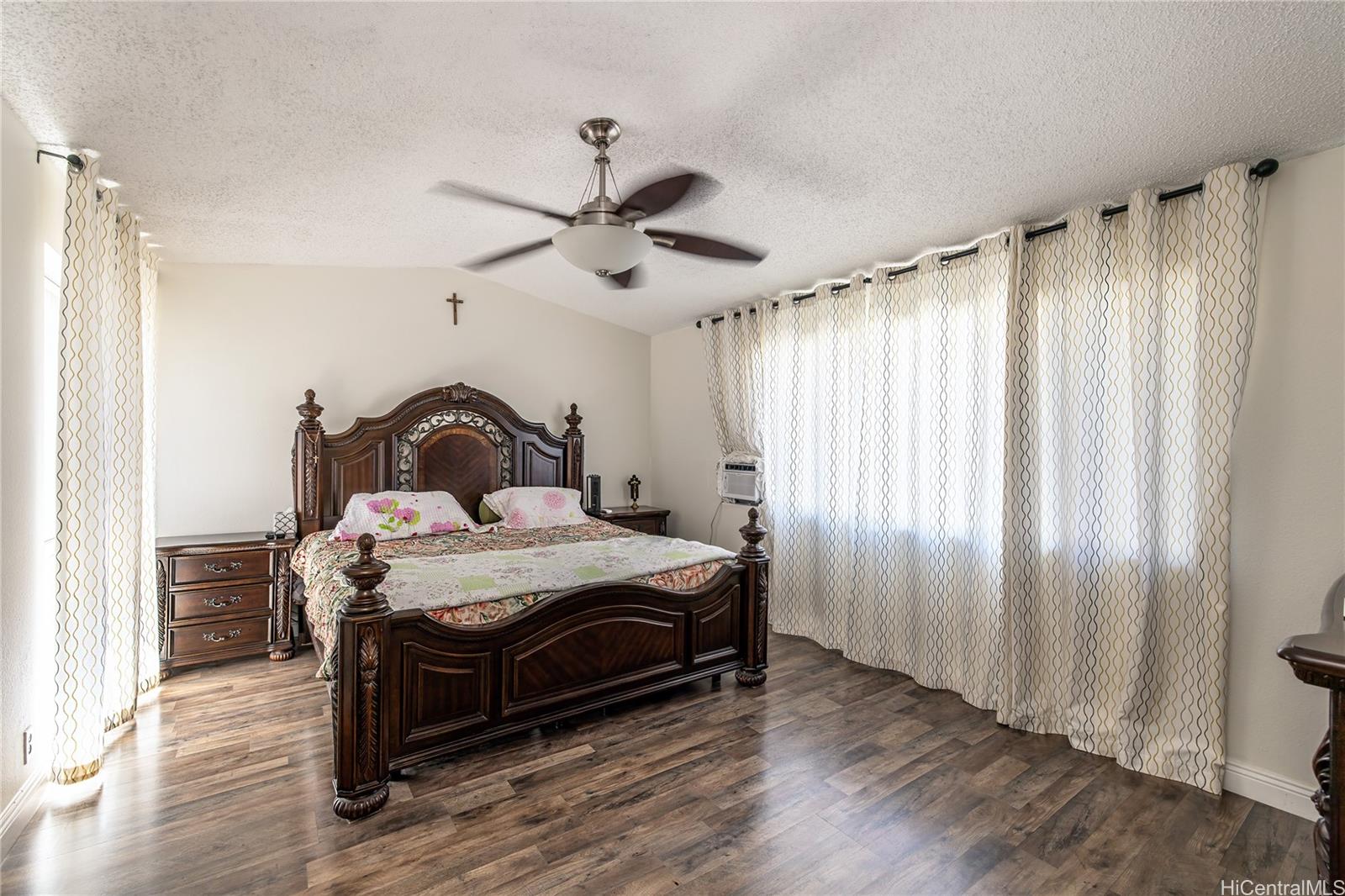 91-957 Laaulu Street, Unit 40F Ewa Beach, HI 96706 - Photo 11 of 22 a bedroom with a bed and a chandelier