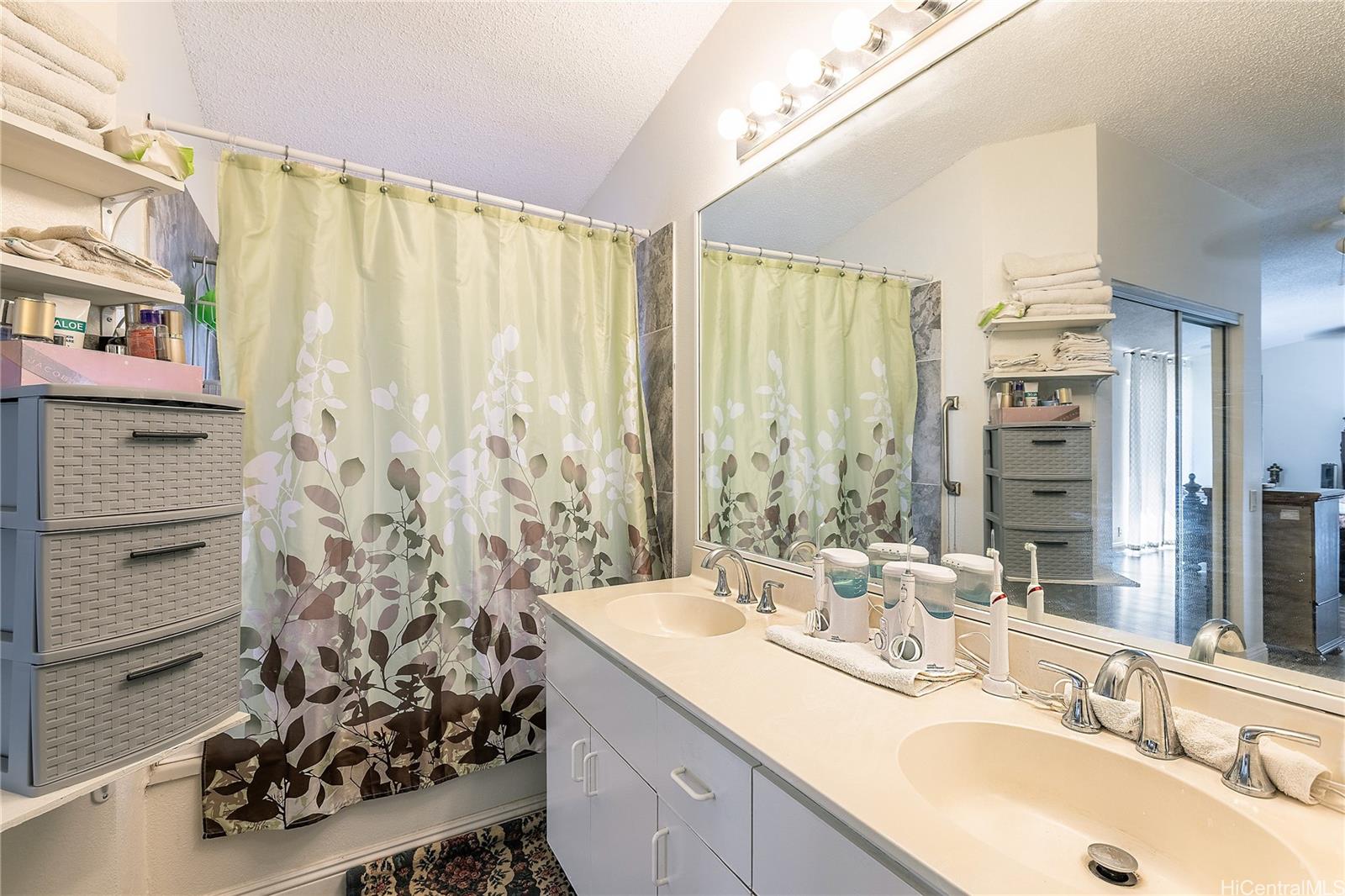 91-957 Laaulu Street, Unit 40F Ewa Beach, HI 96706 - Photo 13 of 22 a bathroom with a double vanity sink a large mirror and shower