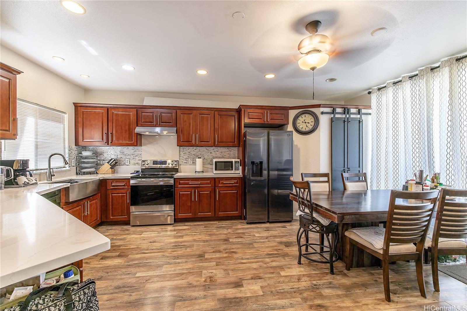 91-957 Laaulu Street, Unit 40F Ewa Beach, HI 96706 - Photo 2 of 22 a kitchen with stainless steel appliances granite countertop a stove top oven a sink a dining table and chairs with wooden floor