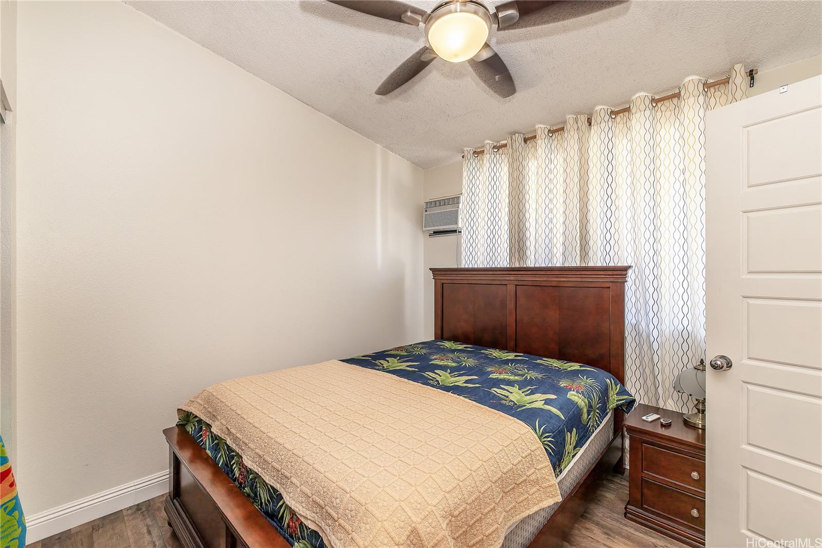 91-957 Laaulu Street, Unit 40F Ewa Beach, HI 96706 - Photo 9 of 22 a bedroom with a bed and a chandelier