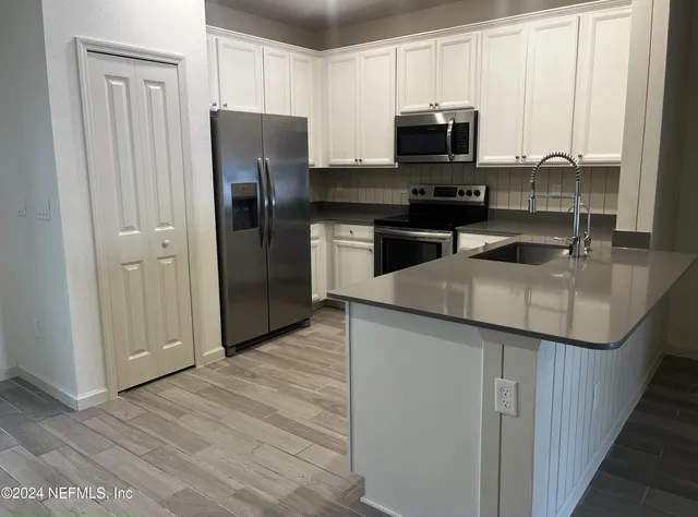 a kitchen with granite countertop a refrigerator and a stove top oven