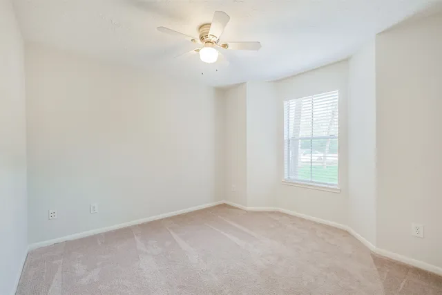 an empty room with windows and ceiling fan