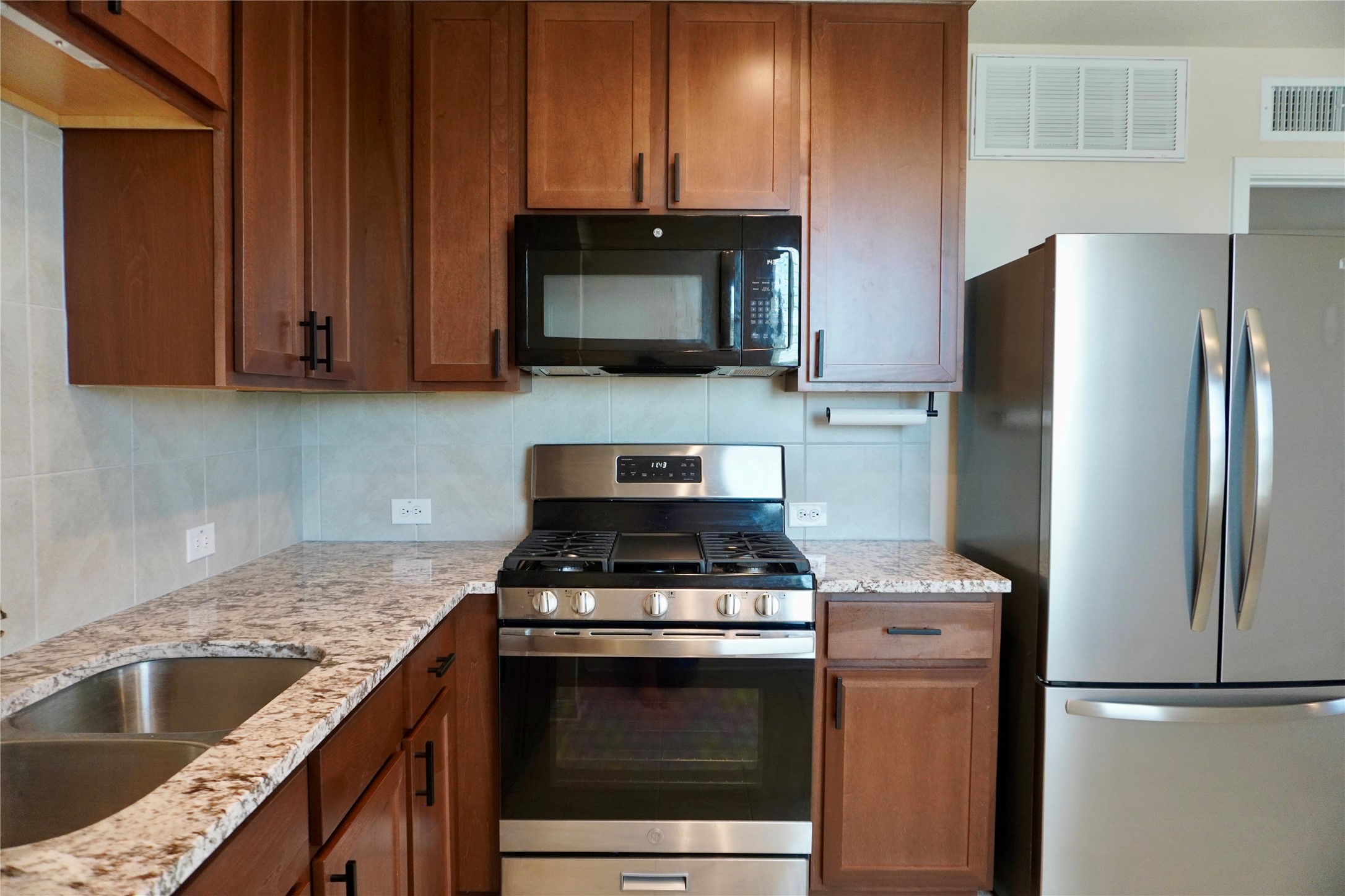 a kitchen with granite countertop a sink stove and refrigerator