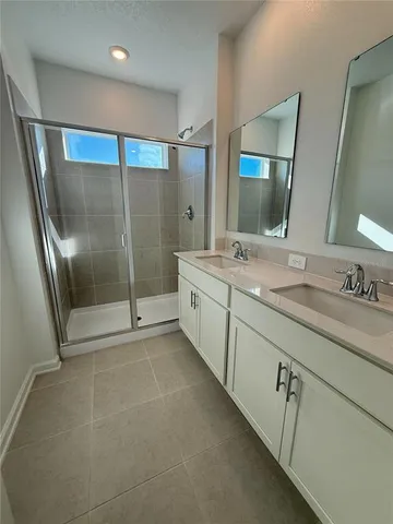 a spacious bathroom with a mirror a shower and a sink