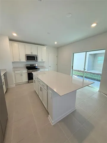 a large kitchen with stainless steel appliances a stove a sink a microwave a refrigerator and cabinets