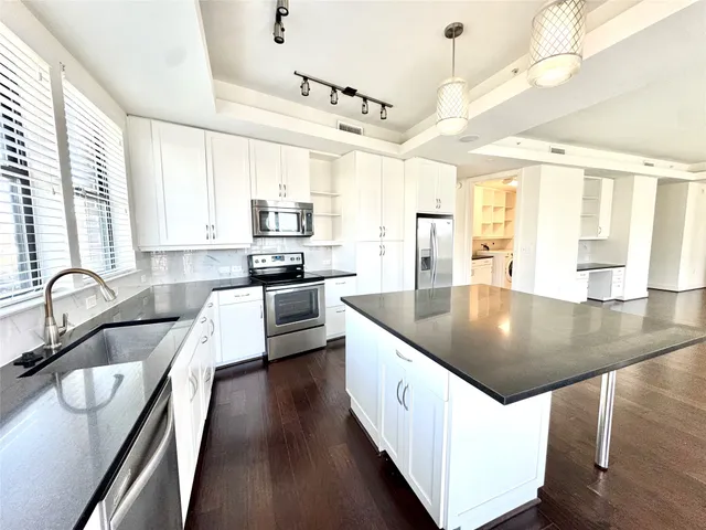 a kitchen with stainless steel appliances granite countertop a sink a stove and a wooden floors