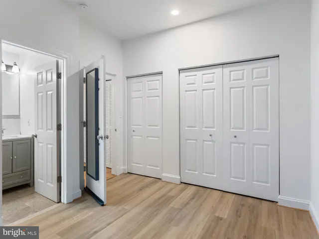 a view of an empty room with wooden floor and a bathroom