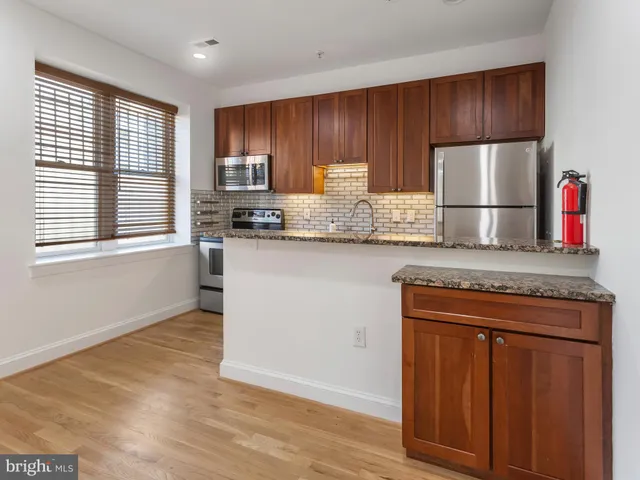 a kitchen with granite countertop wooden cabinets a refrigerator and a stove top oven
