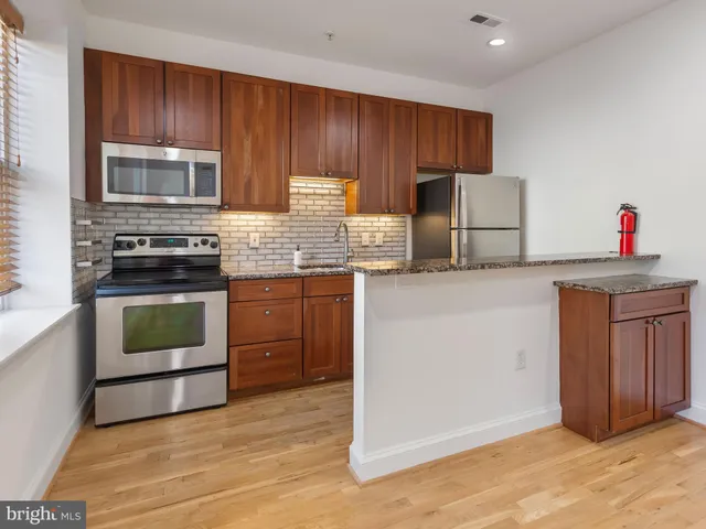 a kitchen with granite countertop wooden cabinets and stainless steel appliances