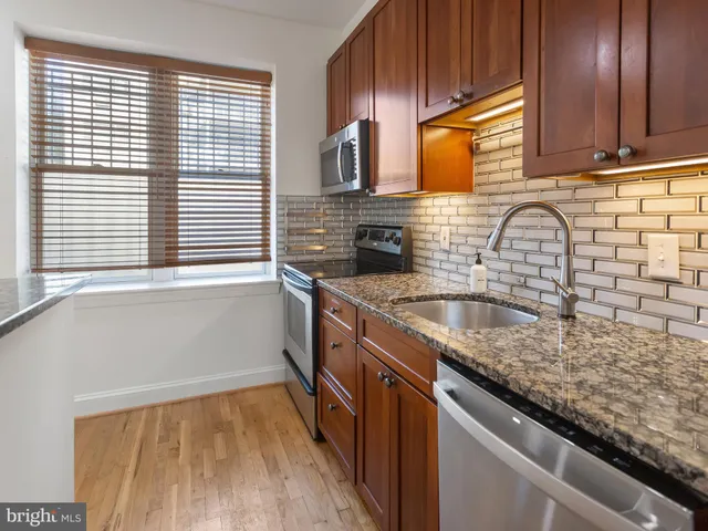 a kitchen with granite countertop a sink a window stainless steel appliances and cabinets
