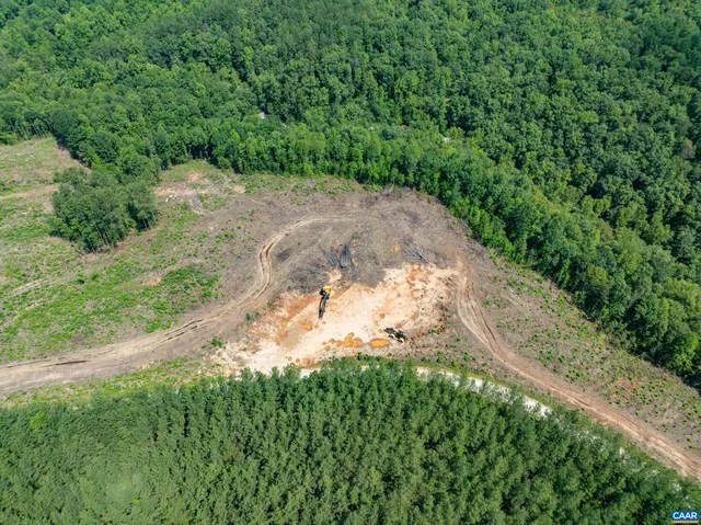 an aerial view of a residential houses with outdoor space and trees