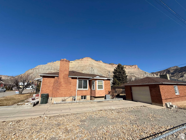 73 Garden Street Helper, UT 84526 - Photo 4 of 36 View of front of house featuring a mountain view, a chimney, an outbuilding, brick siding, and concrete driveway