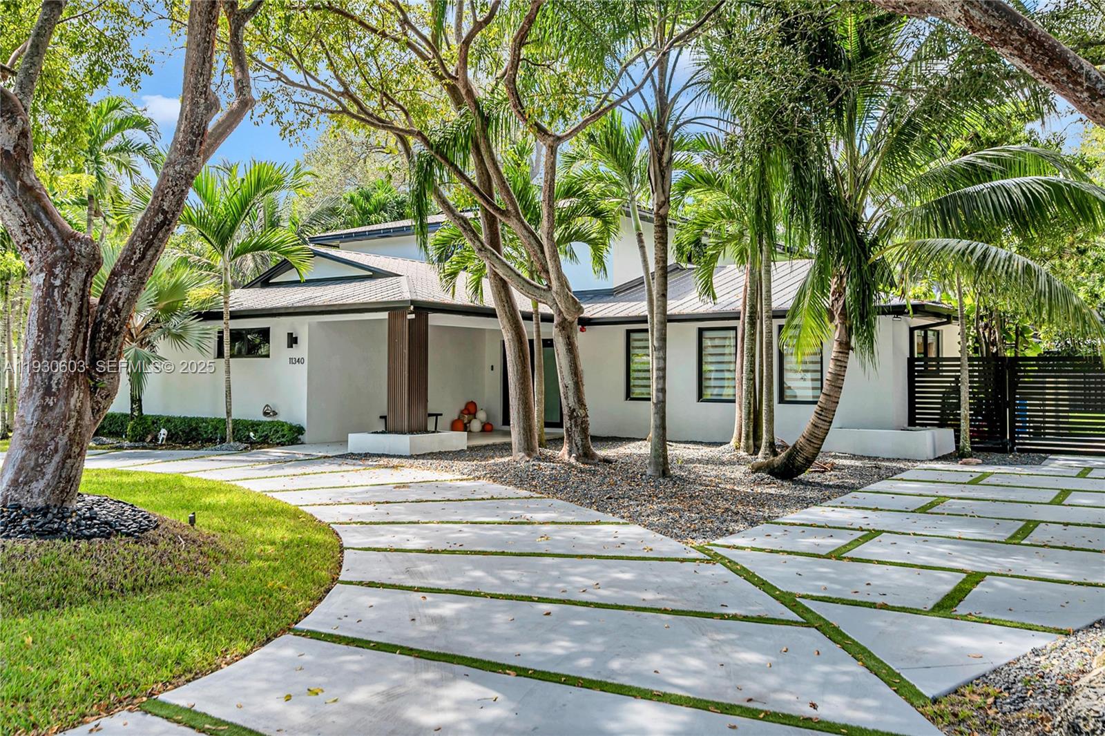 11340 Southwest 74th Court Pinecrest, FL 33156 - Photo 66 of 91 a front view of a house with a yard table and chairs