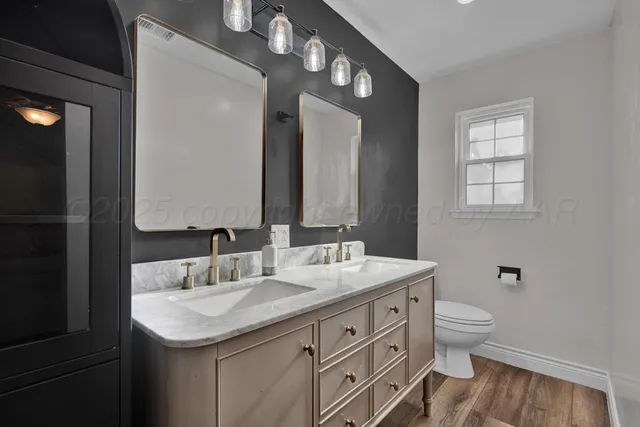 a bathroom with a granite countertop sink a toilet and a mirror