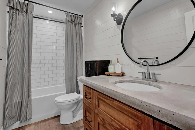 a bathroom with a granite countertop sink a toilet a mirror and shower