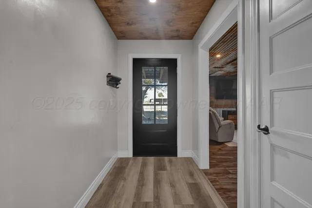 a view of a hallway with wooden floor and a bathroom