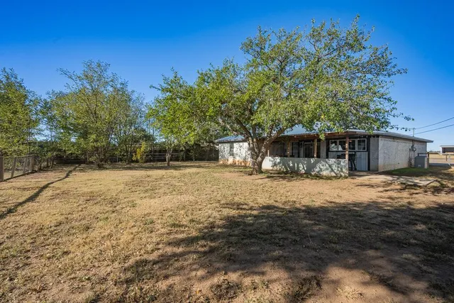 a front view of house with yard and trees in the background