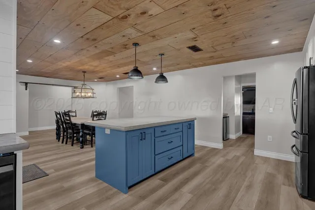 a kitchen with stainless steel appliances granite countertop a table chairs and wooden floor