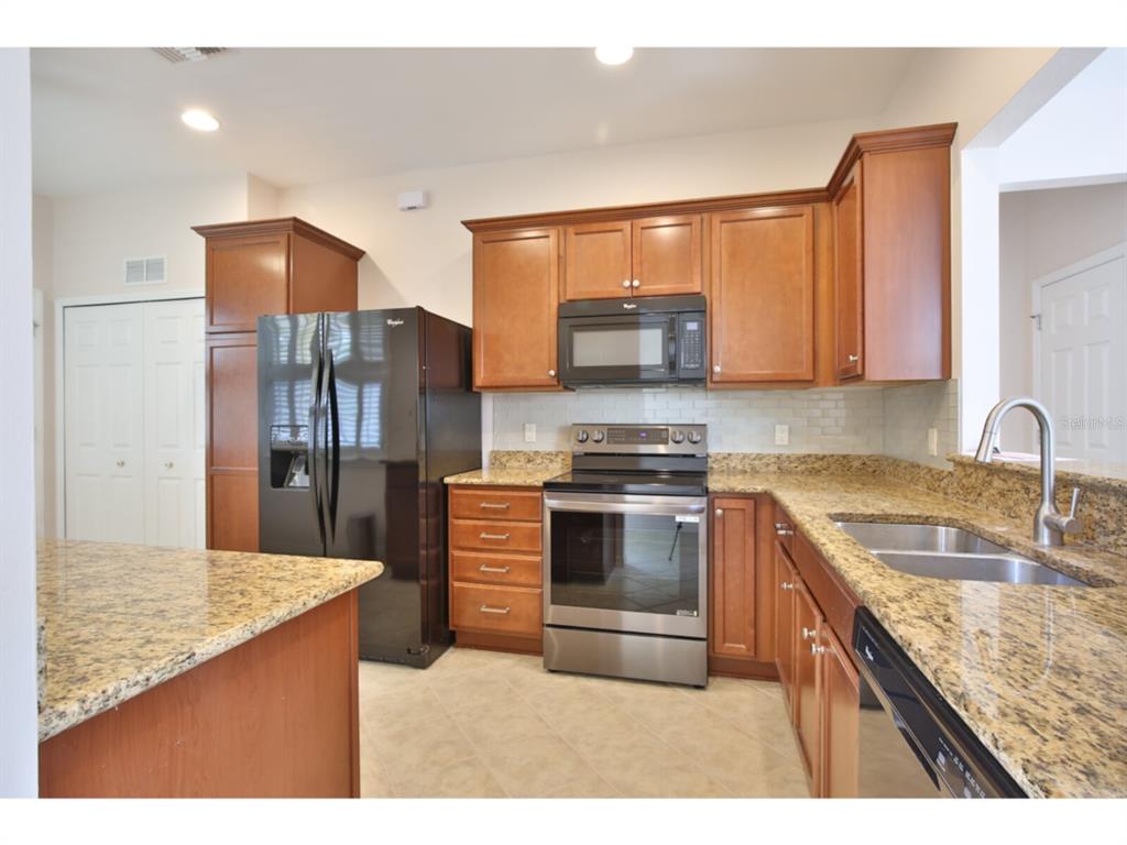 19108 Lappacio Street Venice, FL 34293 - Photo 8 of 33 a kitchen with stainless steel appliances granite countertop a sink stove and refrigerator