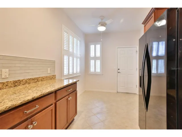 a kitchen with granite countertop a refrigerator a sink and wooden cabinets