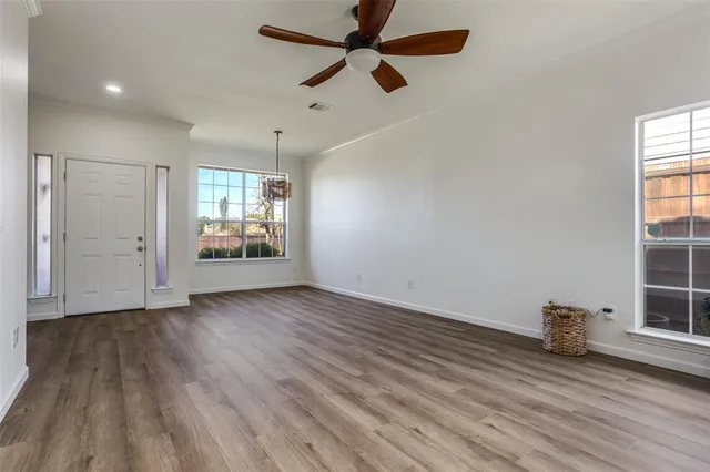 an empty room with wooden floor and windows