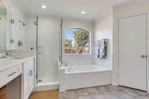 a spacious bathroom with a tub shower sink natural light and a large window