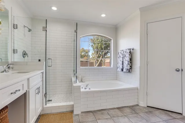 a spacious bathroom with a tub shower sink natural light and a large window