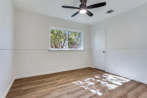 a view of empty room with wooden floor and fan