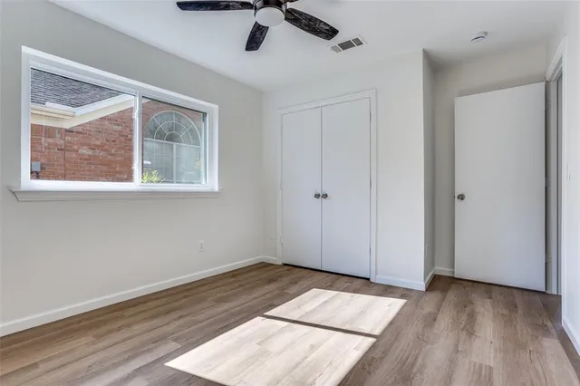 a view of empty room with wooden floor and fan