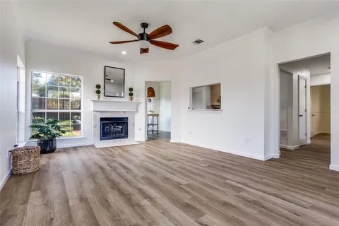 an empty room with wooden floor a ceiling fan and a fireplace