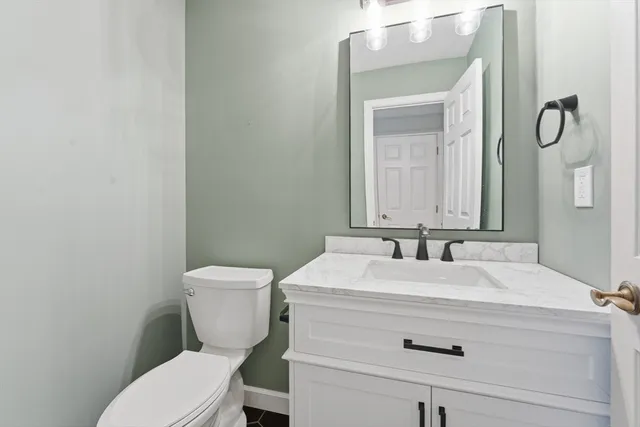 a bathroom with a granite countertop toilet sink and mirror