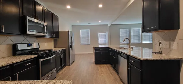 a kitchen with stainless steel appliances granite countertop a stove a sink and a microwave