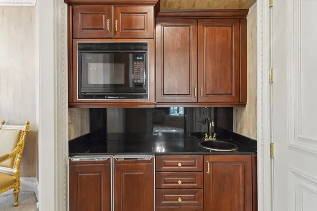 a view of a white house with large trees and wooden fence