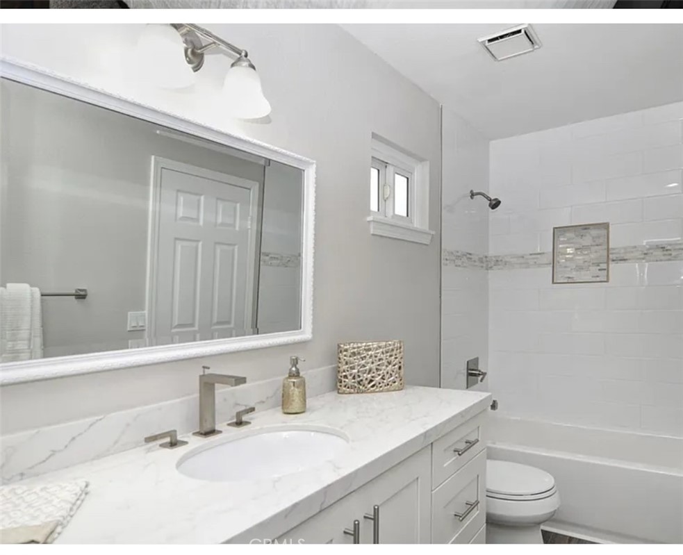 211 8th Street Huntington Beach, CA 92648 - Photo 6 of 16 a bathroom with a granite countertop sink a toilet and a bathtub