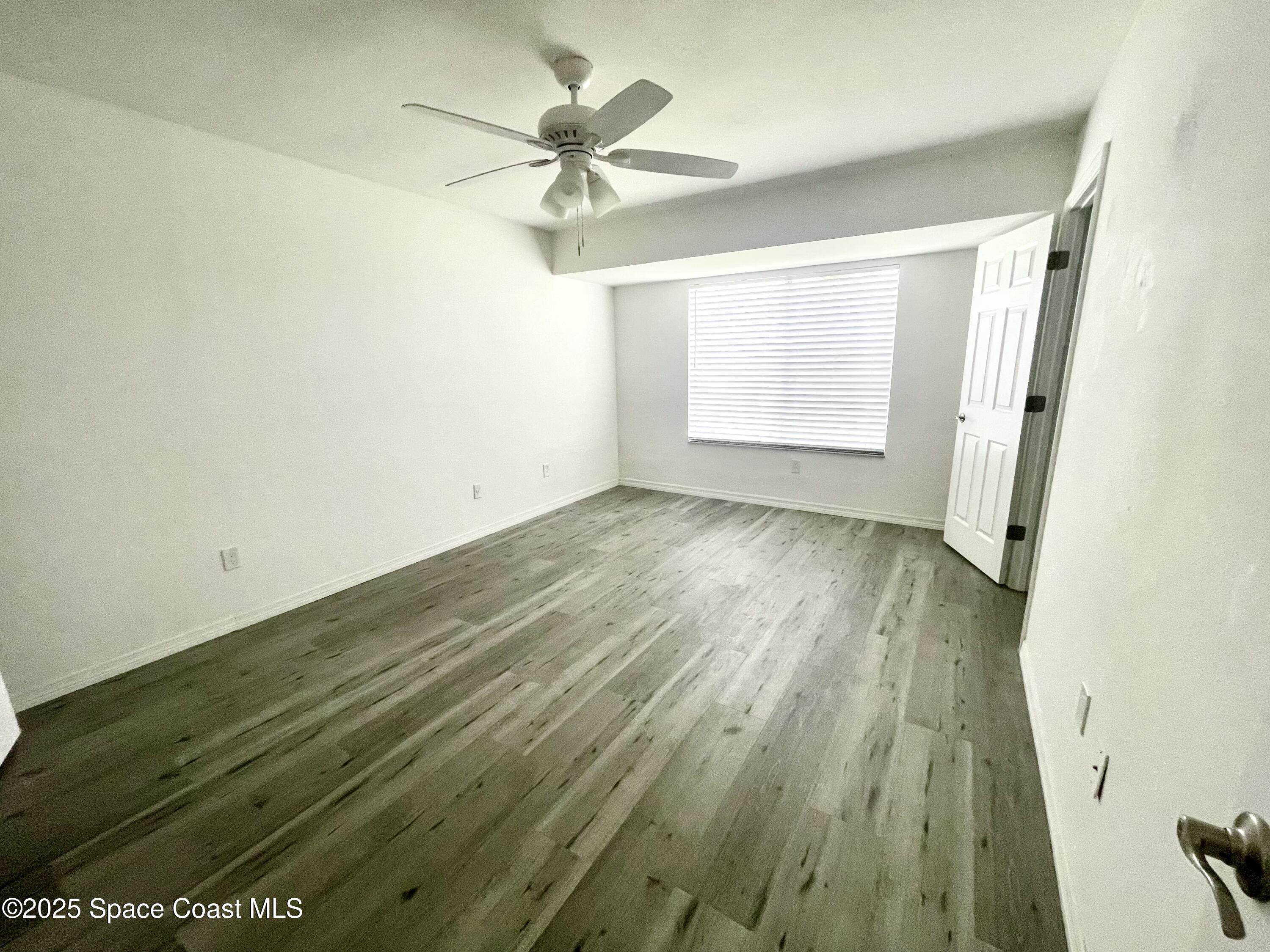 1186 Galty Circle Northeast, Unit 6 Palm Bay, FL 32905 - Photo 13 of 26 an empty room with wooden floor fan and windows