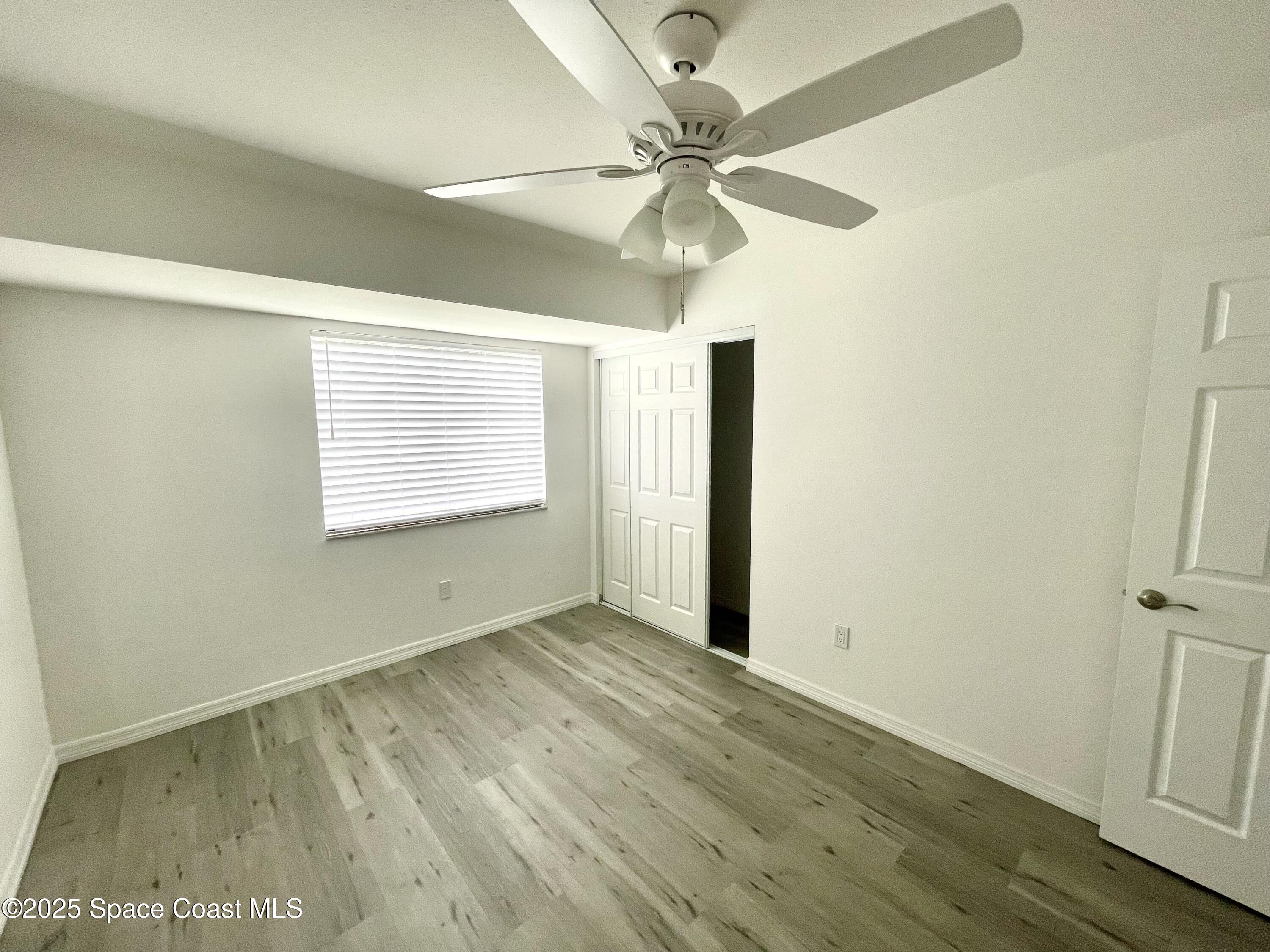 1186 Galty Circle Northeast, Unit 6 Palm Bay, FL 32905 - Photo 17 of 26 a view of an empty room with wooden floor and a window