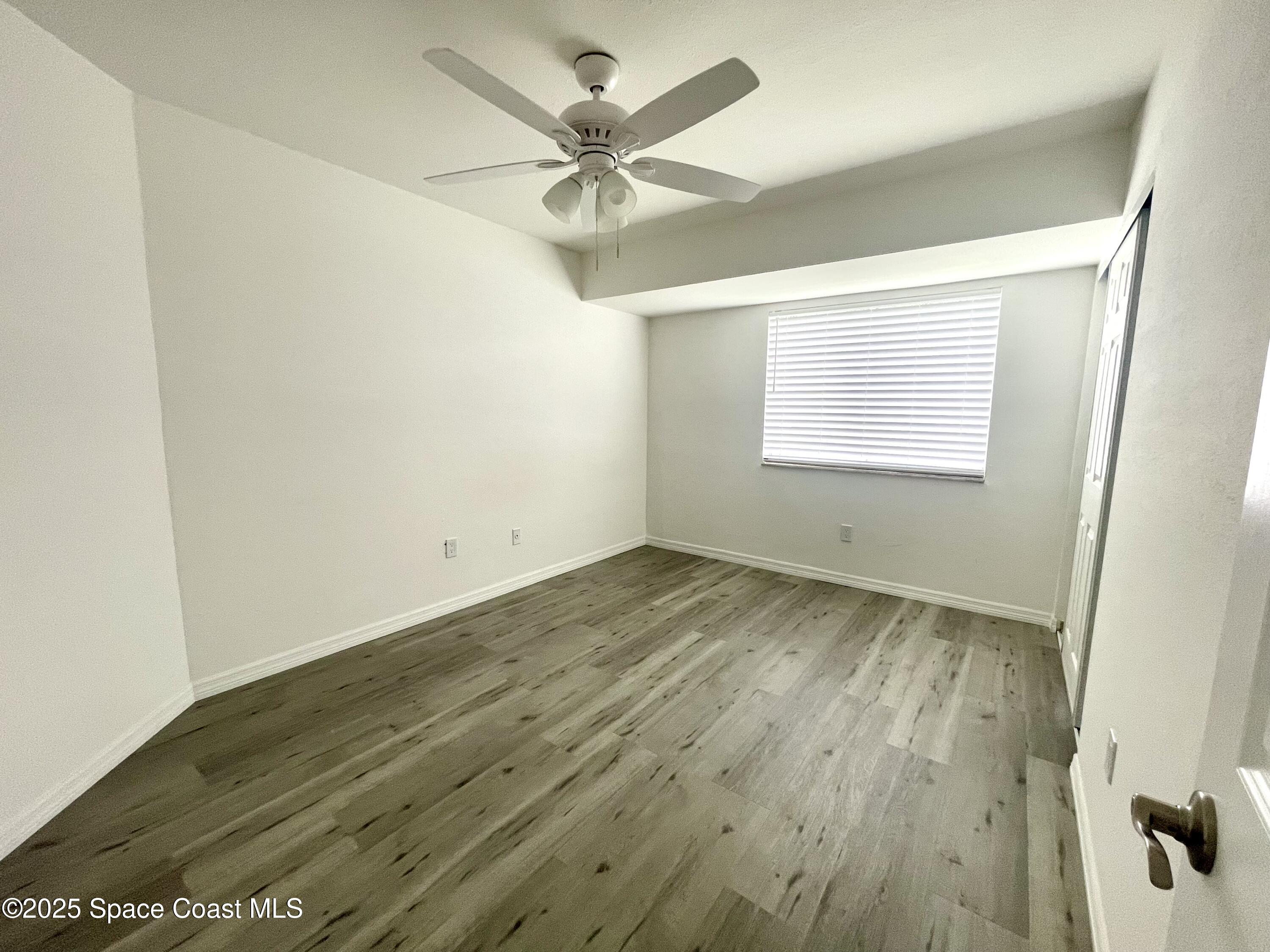 1186 Galty Circle Northeast, Unit 6 Palm Bay, FL 32905 - Photo 18 of 26 an empty room with wooden floor fan and windows