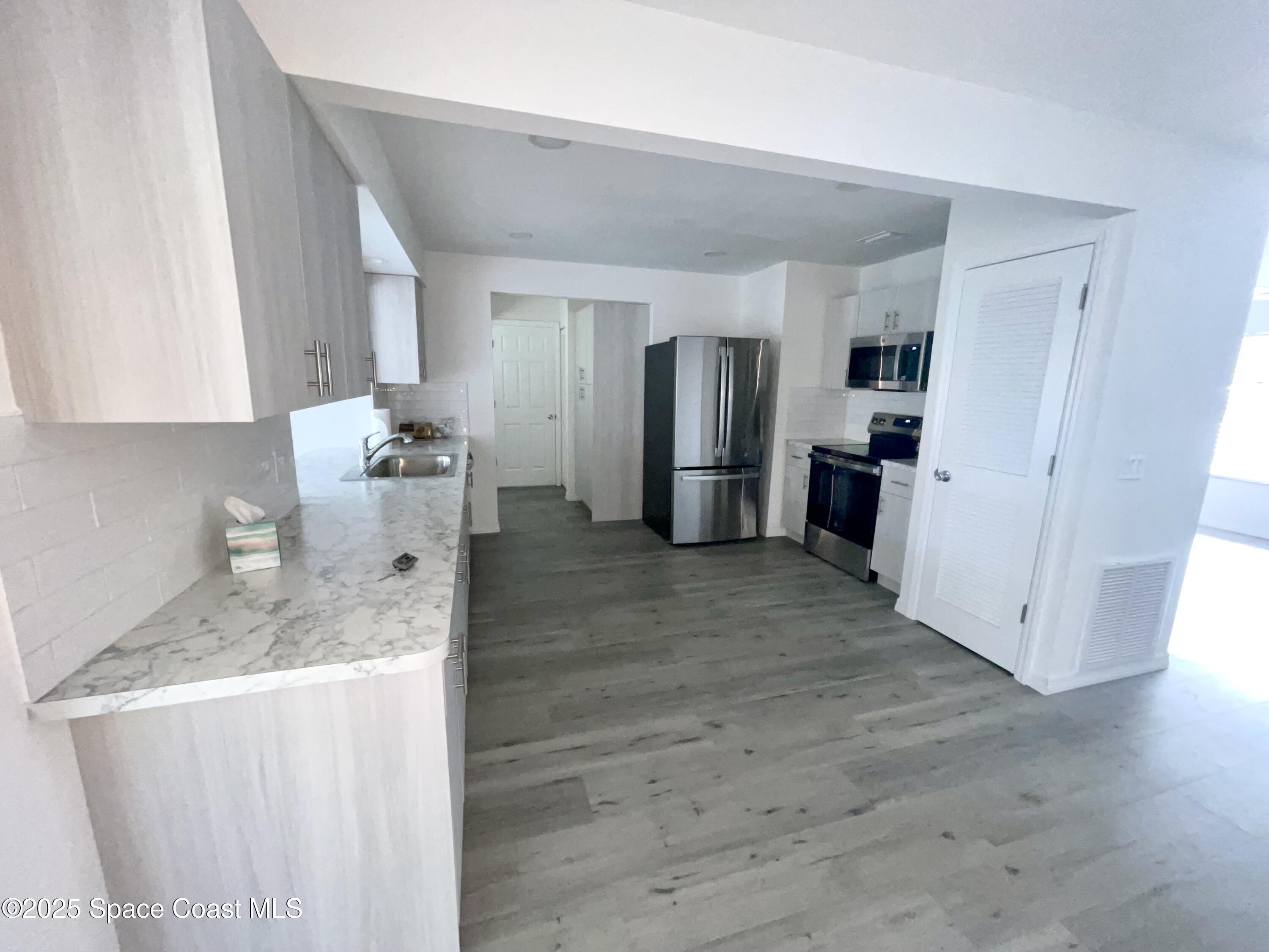 1186 Galty Circle Northeast, Unit 6 Palm Bay, FL 32905 - Photo 6 of 26 a kitchen with stainless steel appliances granite countertop a refrigerator and a stove