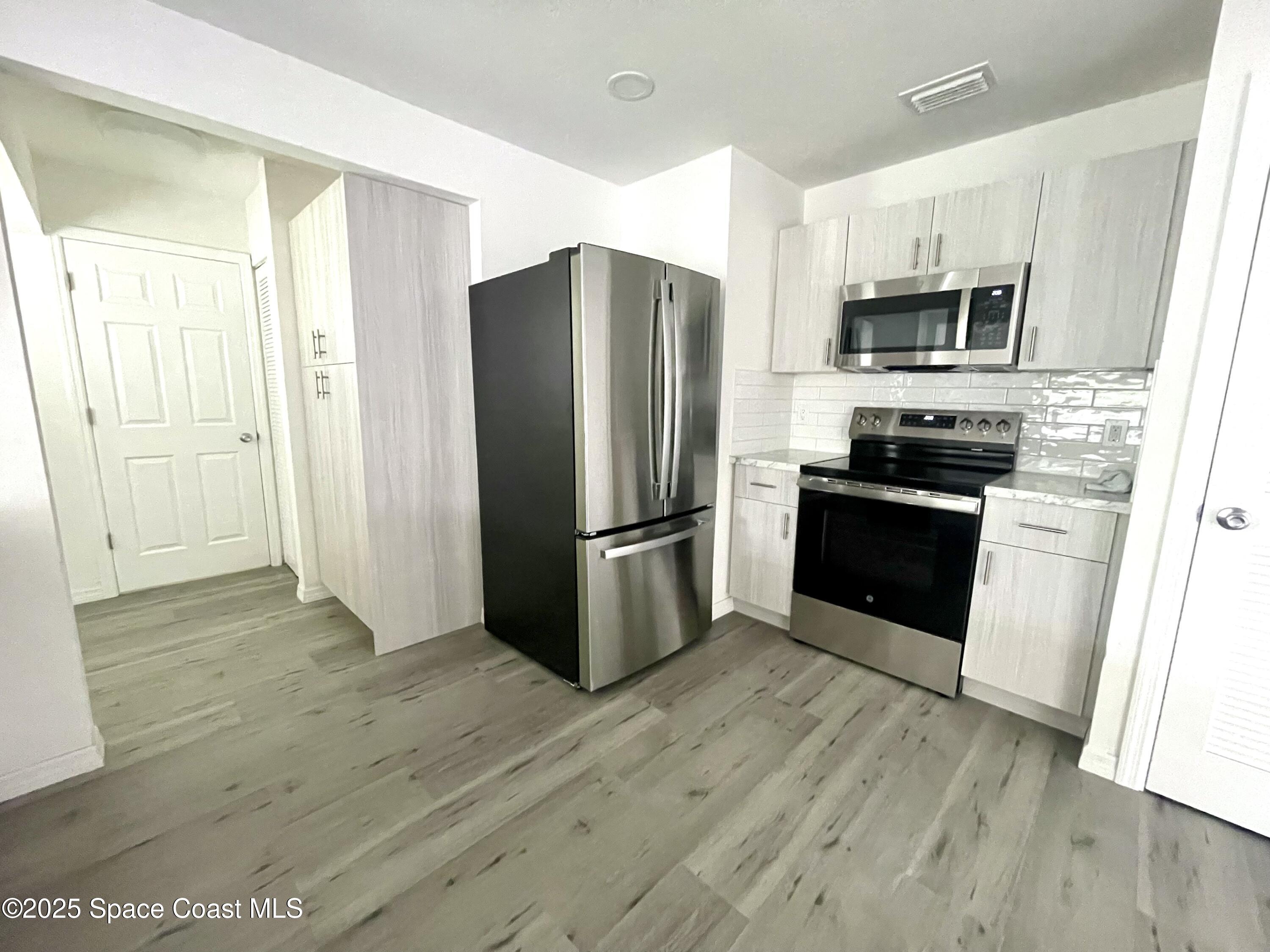 1186 Galty Circle Northeast, Unit 6 Palm Bay, FL 32905 - Photo 8 of 26 a kitchen with stainless steel appliances granite countertop a refrigerator stove and microwave