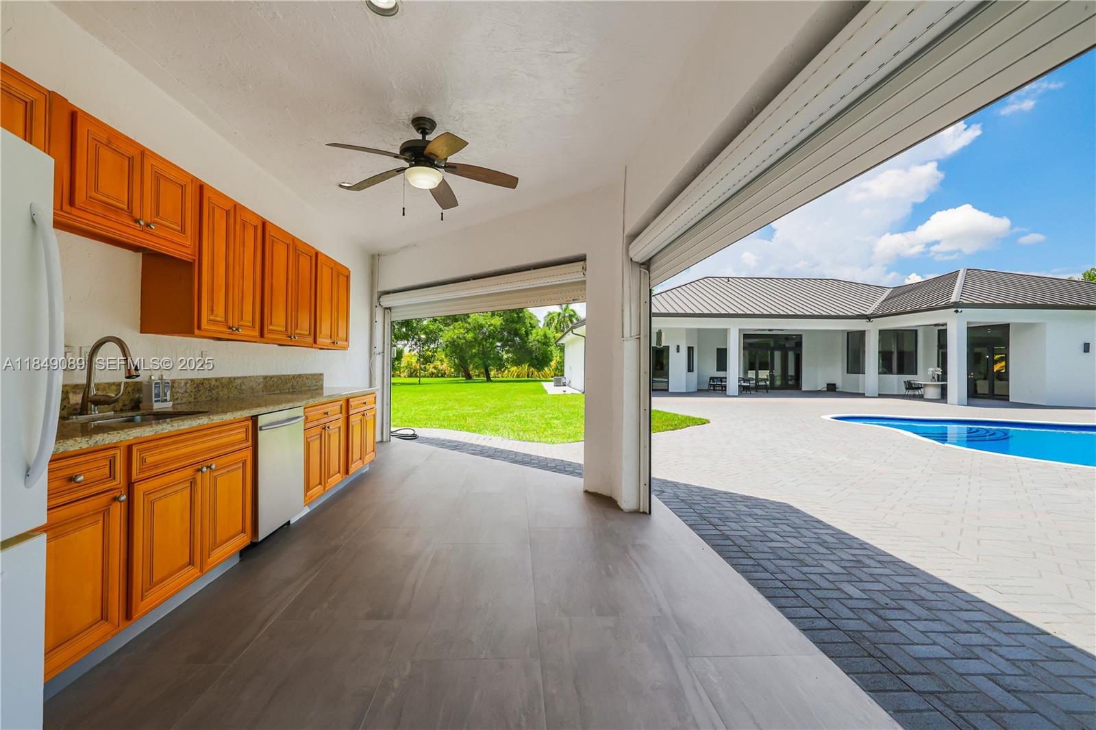 601 Ranch Road Weston, FL 33326 - Photo 53 of 75 Outdoor kitchen features refrigerator and sink facing the pool.