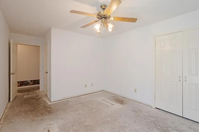 an empty room with a chandelier fan and windows