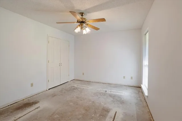an empty room with a chandelier fan and a table
