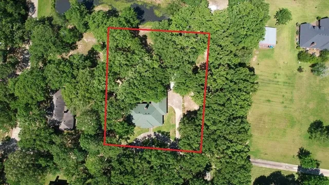 an aerial view of residential house with outdoor space and trees all around