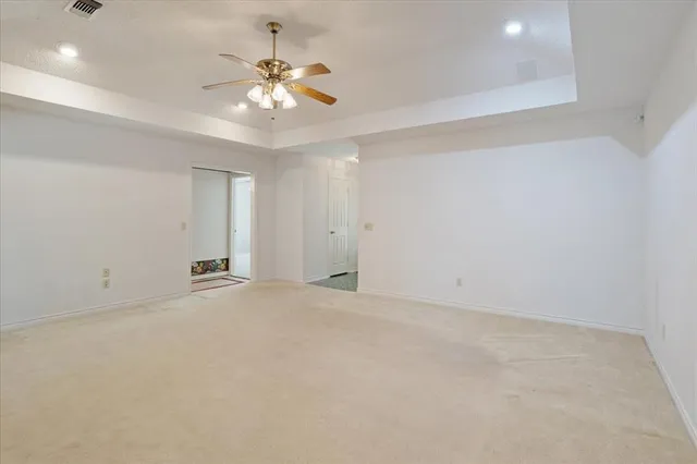 an empty room with chandelier fan and windows