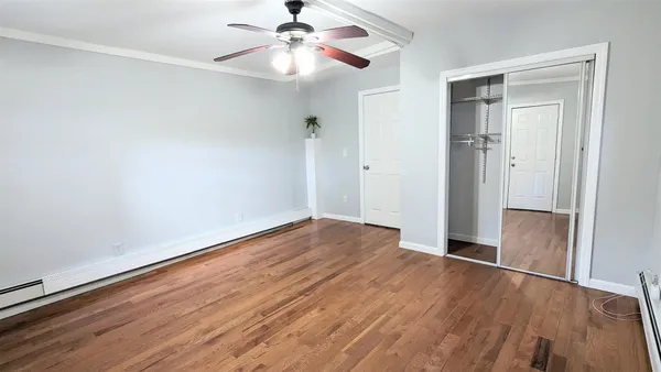 an empty room with wooden floor fan and windows