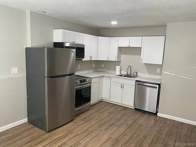 a kitchen with a refrigerator sink and wooden floor