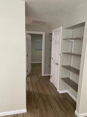 a view of a hallway with wooden floor and closet